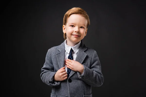Очаровательный улыбающийся мальчик в костюме, изолированном на сером — стоковое фото