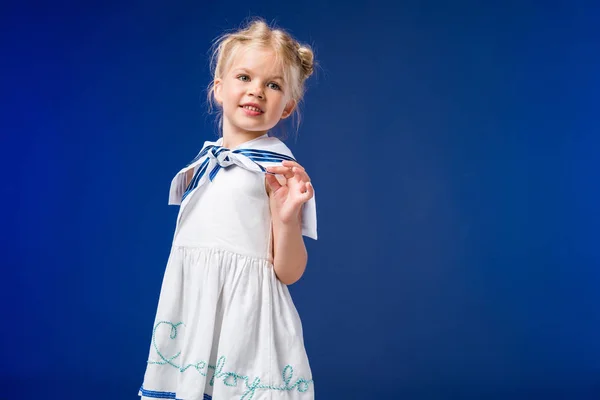 Entzückendes blondes Kind posiert im Matrosenkostüm, isoliert auf blauem Grund — Stockfoto