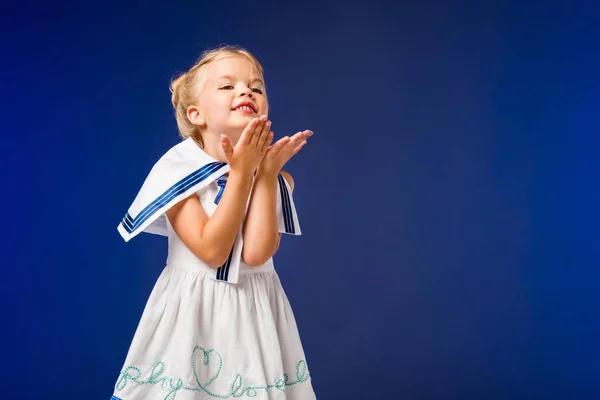 Adorable happy kid in sailor costume blowing kiss, isolated on blue — Stock Photo