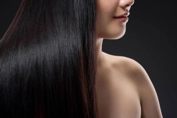 Teilansicht einer lächelnden Frau mit glänzend gesundem und kräftigem Haar isoliert auf schwarz — Stockfoto