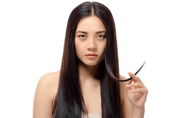 Портрет молодой азиатской женщины с раздвоенными концами, смотрящей на камеру, изолированную на белой, поврежденной концепции волос — стоковое фото
