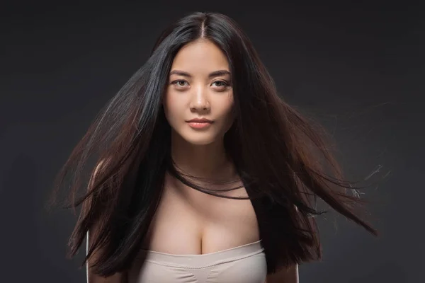 Porträt einer hübschen asiatischen Frau mit gesundem und kräftigem Haar, die isoliert auf schwarz in die Kamera blickt — Stockfoto