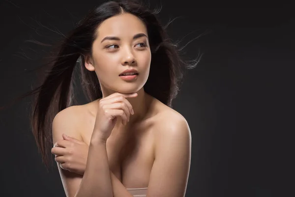 Portrait of pensive asian woman with beautiful and healthy dark hair posing isolated on black — Stock Photo