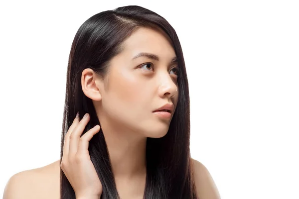 Retrato de modelo asiático pensativo con cabello fuerte y saludable mirando hacia otro lado aislado en blanco - foto de stock