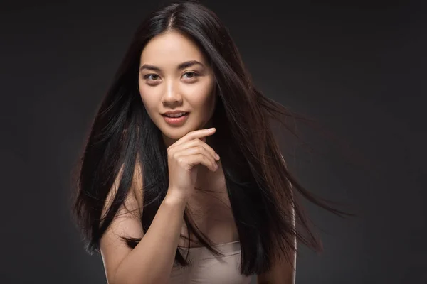 Retrato de joven mujer asiática con hermoso y saludable cabello oscuro mirando a la cámara aislada en negro - foto de stock