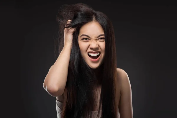 Retrato de emocional asiático mujer con oscuro sano cabello aislado en negro - foto de stock