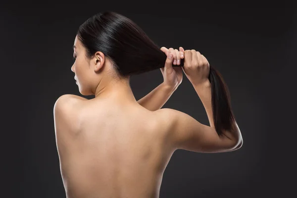 Vista posterior de la mujer sin camisa con hermoso pelo brillante aislado en negro - foto de stock