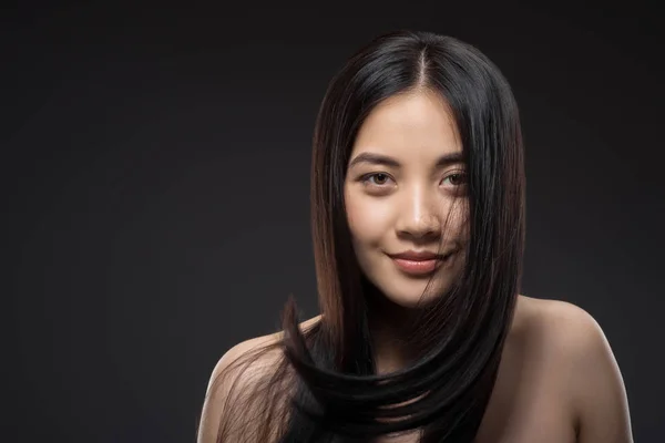 Porträt einer jungen lächelnden Asiatin mit schönen und gesunden dunklen Haaren, die isoliert auf schwarz in die Kamera blickt — Stockfoto
