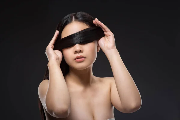 Vue obscurcie de la femme asiatique avec des cheveux noirs en bonne santé isolé sur noir — Photo de stock