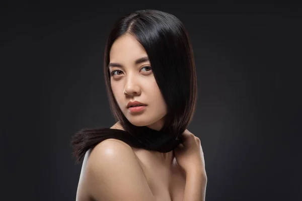 Retrato de joven mujer asiática con hermoso y saludable pelo oscuro posando aislado en negro - foto de stock