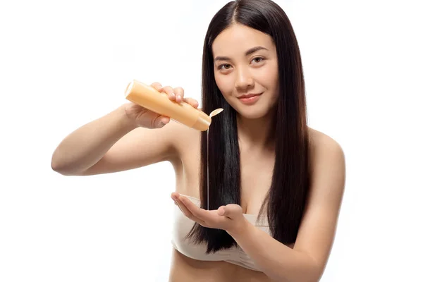 Portrait de jeune femme asiatique versant shampooing à la main isolé sur blanc, concept de traitement des cheveux — Photo de stock