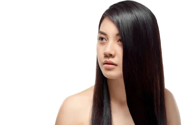 Retrato de mujer asiática joven con cabello hermoso y saludable mirando hacia otro lado aislado en blanco - foto de stock