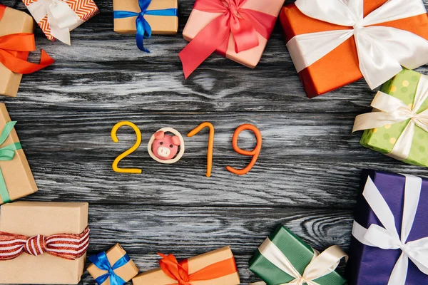 Top view of 2019 symbol and wrapped christmas presents on wooden surface — Stock Photo