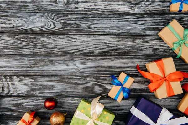 Vue de dessus des cadeaux de Noël et des boules brillantes sur la surface en bois — Photo de stock