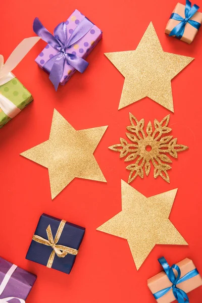 Top view of golden stars, decorative snowflake and christmas presents on red — Stock Photo