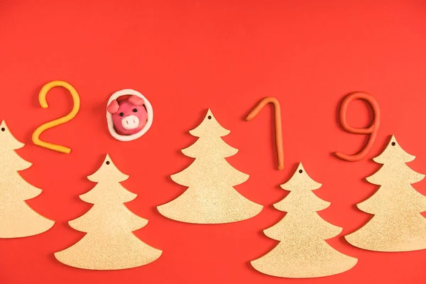 Top view of 2019 symbol, pig and fir trees on red — Stock Photo