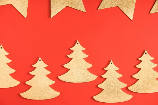 Top view of golden stars and fir trees symbols on red background — Stock Photo