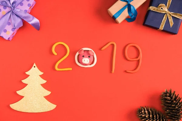 Вид зверху на символ 2019 року, соснові шишки та різдвяні подарунки на червоному — стокове фото