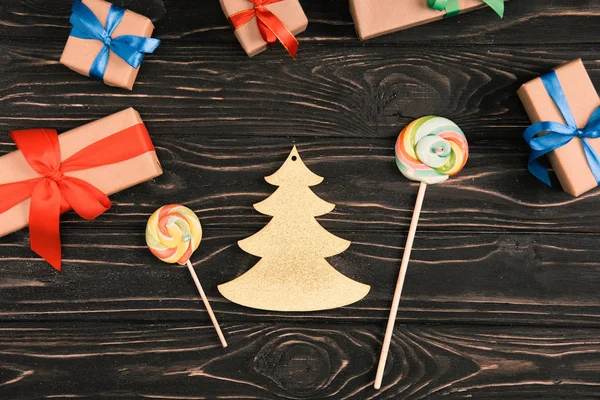 Vista superior de piruletas, símbolo del abeto y regalos de Navidad en la superficie de madera - foto de stock