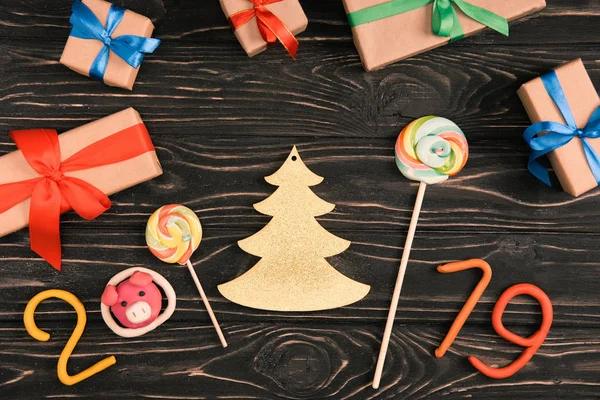 Vue du dessus des sucettes, panneau 2019 et cadeaux de Noël sur la surface en bois — Photo de stock