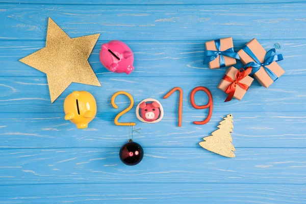 Sparschweine, Weihnachtsgeschenke und 2019-Symbol auf blauer Holzoberfläche — Stockfoto