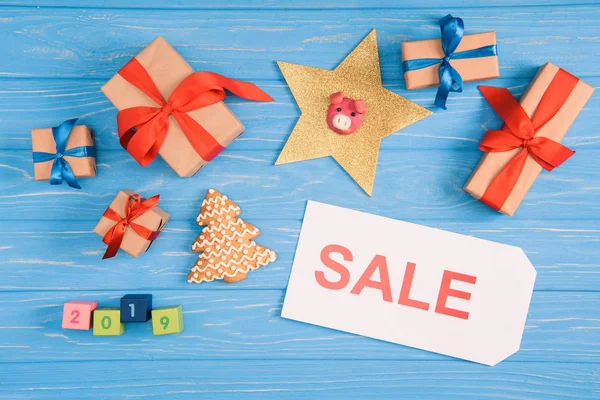 Верхний вид на знак продажи, рождественские подарки и пряничное печенье на голубой деревянной поверхности — стоковое фото