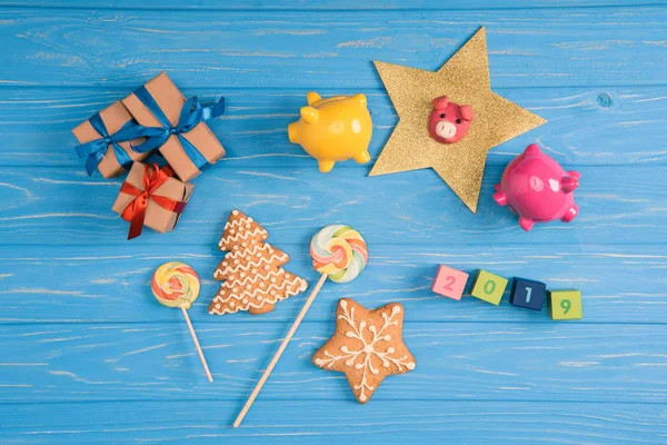 Vue du dessus des cadeaux de Noël, bonbons, cochons et 2019 sur cubes sur surface en bois bleu — Photo de stock