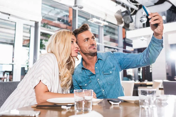 Feliz pareja tomando selfie con teléfono inteligente durante la fecha en la cafetería - foto de stock