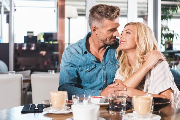 Glückliches Paar umarmt und küsst sich am Tisch im Café — Stockfoto