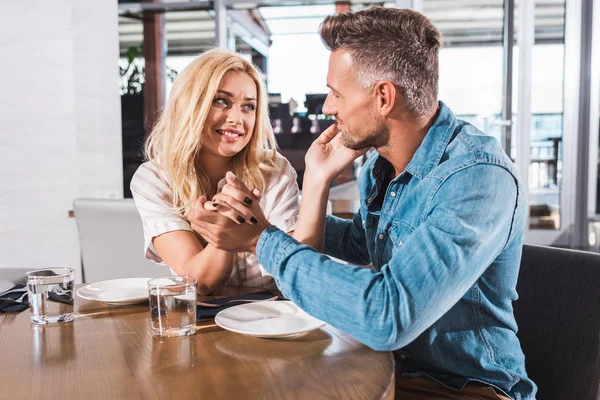 Coppia felice che si tiene per mano a tavola nel caffè, fidanzata toccare faccia fidanzato — Foto stock