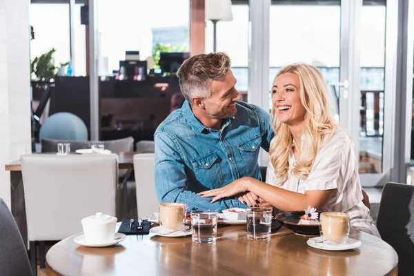 Feliz rindo casal de mãos dadas e passar tempo à mesa no café — Fotografia de Stock