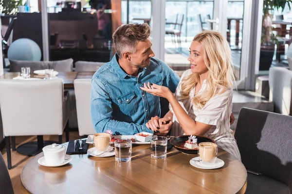 Casal feliz de mãos dadas e falando à mesa no café — Fotografia de Stock