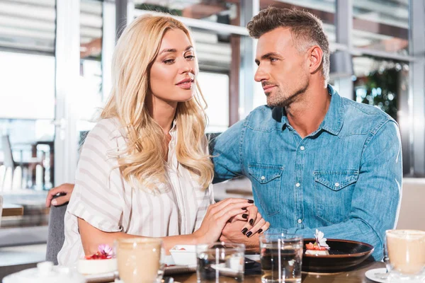 Affectionate happy couple holding hands during date in cafe — Stock Photo