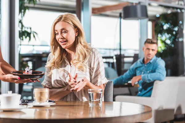 Femme blonde surprise regardant dessert avec fleur au restaurant — Photo de stock