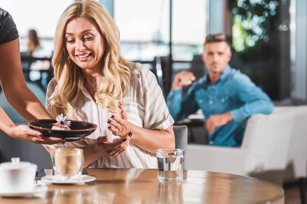 Surprised happy woman looking at dessert with flower in cafe — Stock Photo