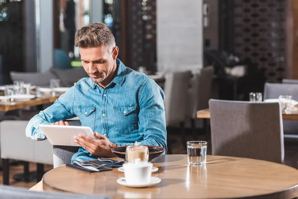 Homem bonito usando tablet no café — Fotografia de Stock