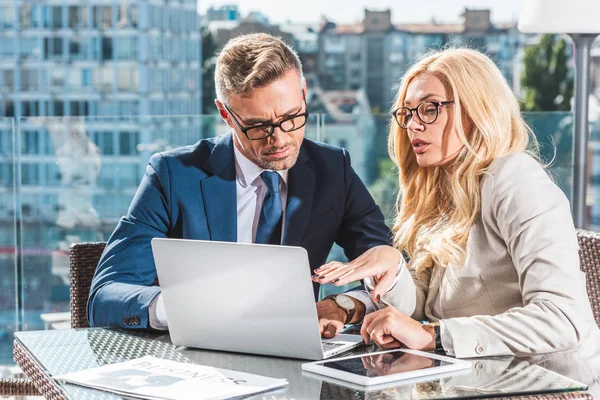 Colleghi di lavoro fiduciosi che utilizzano il computer portatile durante la riunione di lavoro nel caffè — Stock Photo