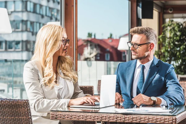 Femme d'affaires avec ordinateur portable ayant une réunion avec un partenaire d'affaires dans un café — Photo de stock