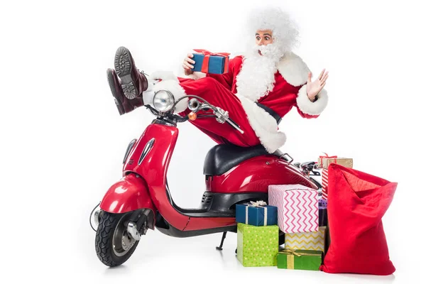 Shocked santa claus in costume sitting on scooter with christmas present isolated on white background — Stock Photo