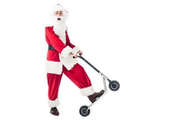 Surpised santa claus in costume riding on kick scooter isolated on white background — Stock Photo