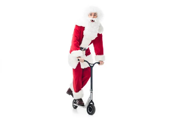 Shocked santa claus in costume riding on kick scooter isolated on white background — Stock Photo