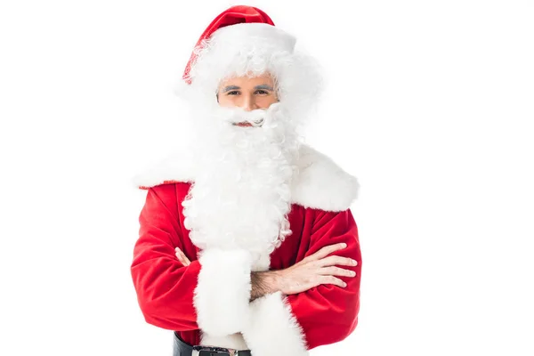 Улыбающийся Санта-Клаус в традиционном костюме, стоящий со скрещенными руками на белом фоне — стоковое фото
