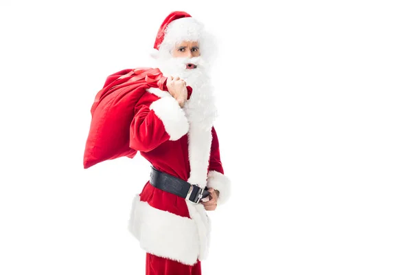 Shocked santa claus holding christmas sack over shoulder isolated on white background — Stock Photo