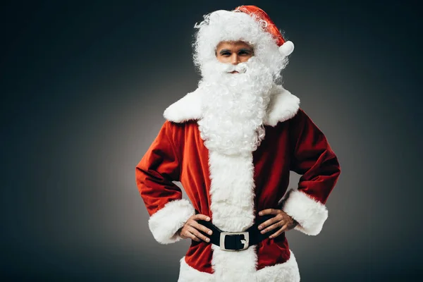 Selbstbewusster Weihnachtsmann im Kostüm, die Hände auf der Taille isoliert auf grauem Hintergrund stehend — Stockfoto