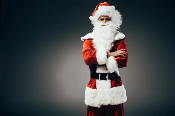 Santa claus en costume debout avec les bras croisés isolés sur fond gris — Photo de stock