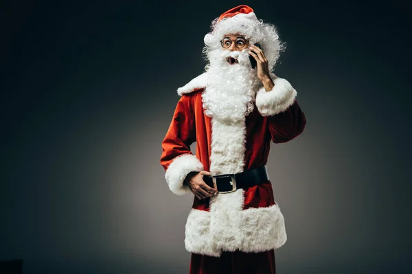 Chocado santa claus no traje falando no smartphone isolado no fundo cinza — Fotografia de Stock