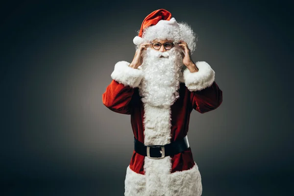 Cheerful santa claus in costume holding hands near beard isolated on grey background — Stock Photo