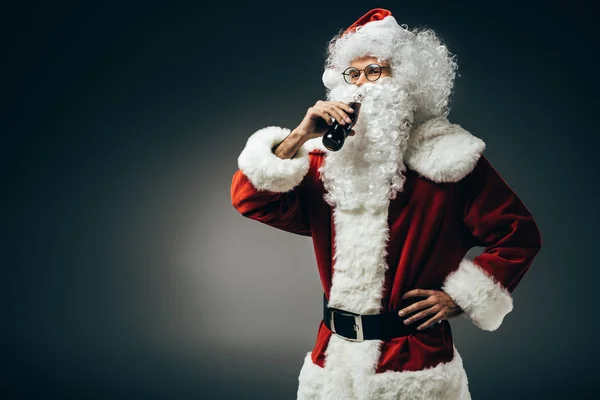 Santa claus en traje de beber soda crema aislado sobre fondo gris - foto de stock