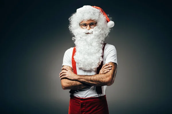 Santa claus dans des lunettes debout avec les bras croisés isolés sur fond gris — Photo de stock