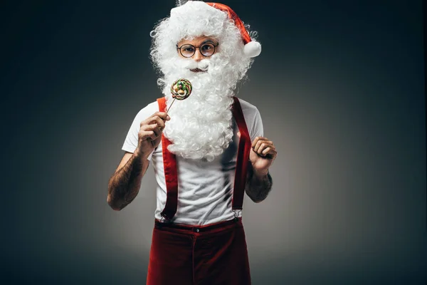 Santa claus dans des lunettes debout avec sucette colorée isolé sur fond gris — Photo de stock